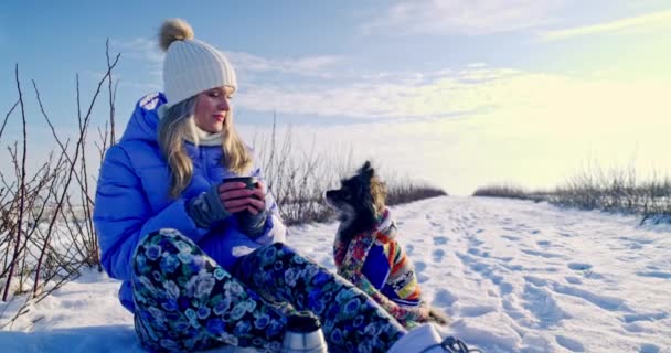 Uma Jovem Mulher Loira Sorridente Senta Neve Com Seu Cão — Vídeo de Stock