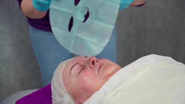 Esteticista Coloca Uma Máscara Rosto Uma Mulher Deitada Uma Cama — Vídeo de Stock