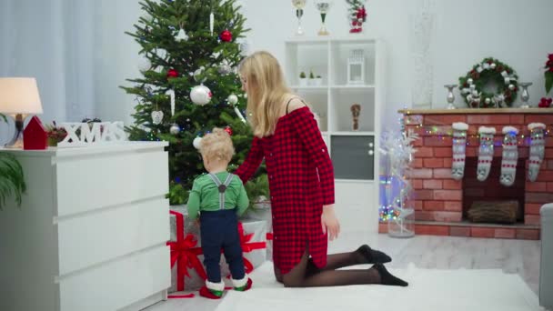 Ung Pojke Tittar Julgranen Och Gåvorna Den Bredvid Honom Mattan — Stockvideo
