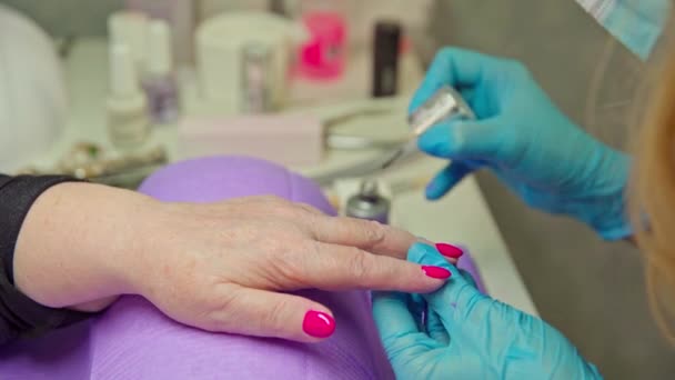 一个女人把手放在紫色的枕头上 对面坐着一位正在画指甲的造型师 造型师在客户的指甲上涂上光滑的上衣 — 图库视频影像