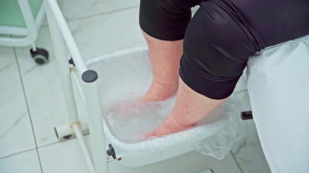 美容トリートメントのための足の皮膚を準備します 美容室の女性が足湯を体験する 暖かい水で足を浸しながらリラックス — ストック動画