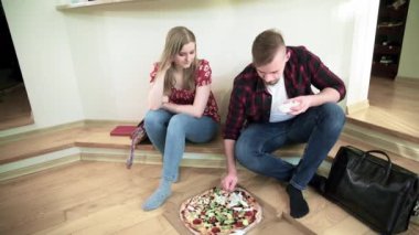 Bir kız ve bir erkek pizza yiyecekler. Çift yan yana oturuyor, ve önlerine bir pizza yerleştiriliyor. Adam pizzaya sarımsak sosu koyuyor..