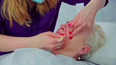 Ağda kullanarak burnun altındaki kılların acı verici bir şekilde alınması. Güzellik uzmanı balmumunu müşterilerinin üst dudağına sürer. Daha sonra balmumuna bir yama yapıştırıyor ve güçlü bir şekilde çekiyor..