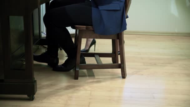 旁边走着一个穿着典雅的黑色闪亮高跟鞋的女人 从女性和男性的腰部向下看 这个人坐在钢琴边弹琴 — 图库视频影像