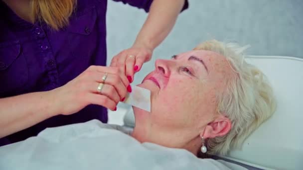 在专业的美容院里 对精致面部肌肤的描述效果最好 沙龙的服务对象躺在一张化妆品床上 接受打蜡治疗 — 图库视频影像