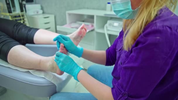 女性は美容室のベッドに横たわっています 女性の足の視点 粒子を剥離した製品によるケラチン化皮膚の除去 — ストック動画