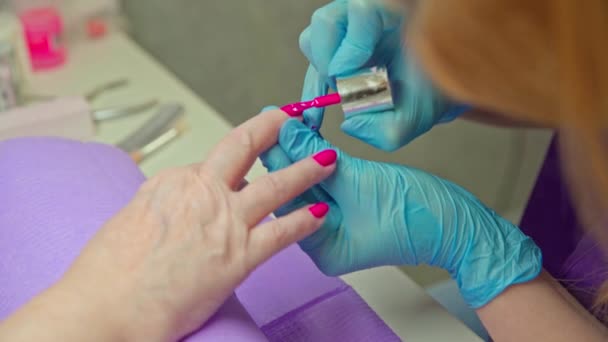 一位顾客使用美容院的服务 将她的手放在一个特殊的垫子上 美容师把顾客的指甲涂成粉红色 — 图库视频影像