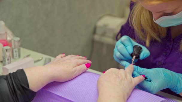 一个成熟的女人来到美容院进行混合修指甲 女人的手的特写 她的手放在紫色的枕头上 — 图库视频影像