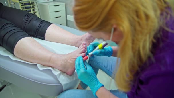 ブレイクされた前景 美容師として働く女性がペディキュアを行います 彼女はつま先から死んだ皮膚を取り除くために爪カッターを使用しています — ストック動画