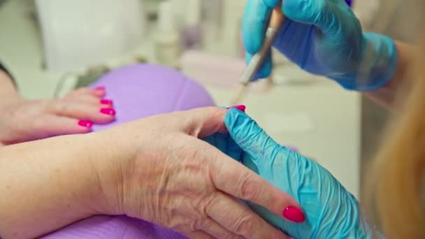 美容院的工作人员用文件抚平客户的指甲 使用美容师服务的妇女的手部特写 一个在美容院里的成熟女人 — 图库视频影像