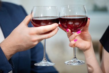 İki kişi şarap bardaklarını tıkırdatıyor. Bir erkek ve bir kadın kadeh kaldırır. Kadının dikkatli bir manikürü var. O, tırnaklarını pembe ojeyle boyattı. Adam mavi bir ceket giyiyor..