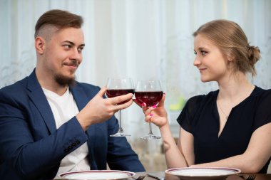 Masada bir kadın ve bir erkek birlikte. Kadehlerini tokuşturup birbirlerinin gözlerine bakarlar. Çift zarif giysiler giyiyor. Arka planda perde ile korunan bir pencere görülebilir.