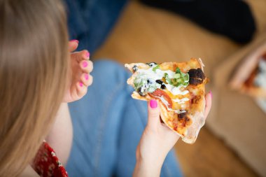 Elinde bir dilim pizza tutan bir kadın figürü. Geniş yakın plan. Zeytin, domates sosu ve salamlı bir dilim pizzaya odaklan..