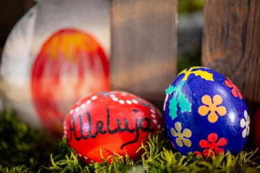 Resmin ön planında, iki el yapımı Paskalya yumurtası spot ışıklarını çalıyor. Bir yumurta, karmaşık çiçek desenleri ile süslenmiş koyu lacivert bir renge sahiptir, diğeri ise canlı kırmızı bir renge sahiptir.