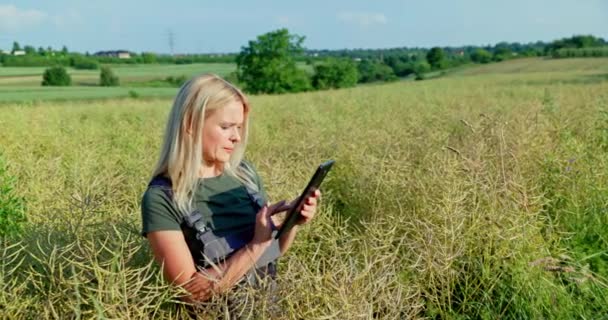 女性農家はタブレットを使用して シーズンの収穫量と利益を評価します 彼女は収穫を予測し 専用の農業アプリを使用して品質をチェックし 高い基準を確保します — ストック動画