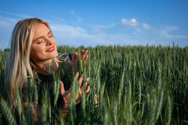 stock image On a sunny day, a young and attractive female farmer stands in her wheat field, overseeing her bountiful crops. Dressed in practical work attire, her blonde hair catching the sunlight, she exudes a