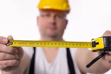 Bir inşaat işçisi, inşaat projelerinde hassasiyetin önemini vurgulayan bir bant ile ölçüm yapar.