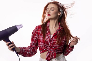 Şık bir kadın saçını saç kurutma makinesiyle kurulamaktan zevk alır, bir stil ve güzellik anı yakalar..