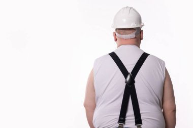 Bir inşaat işçisi emniyet kaskı ve pantolon askısı takıyor ve sektöre hazır olduklarını gösteriyor.