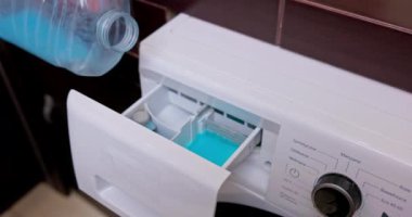 Bu, mavi sıvı deterjanla dolu bir çamaşır makinesinin deterjan çekmecesini gösteren yakın çekim görüntüsü.