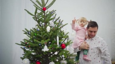 Sevgi dolu bir baba ve çocuğu arasında güzel süslenmiş bir Noel ağacı tarafından paylaşılan neşeli bir an.