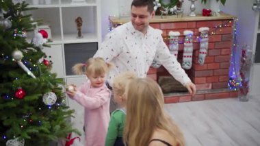 Çocukların güzel dekore edilmiş Noel şöminesinin etrafında oynadığı mutlu bir ailenin yürek ısıtan ve neşeli bir sahnesi.