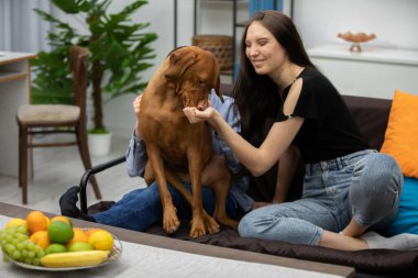 Bir kadın sevgi dolu bir şekilde sevgili köpeğiyle meşgul, sıcaklığını, sevgisini ve dostluğunu gösteriyor.