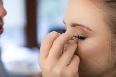 Göz makyajı yapan bir makyözün yakın çekimi olağanüstü güzellik teknikleri ve becerileri sergiliyor.