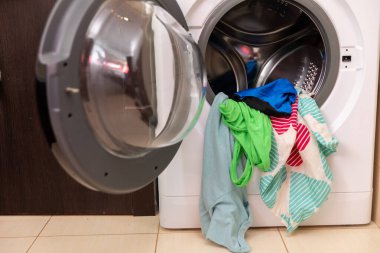 Canlı ve renkli giysilerle dolu bir çamaşır makinesi eksiksiz ve ferahlatıcı bir yıkama için hazır.