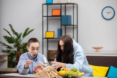 İki çocuk neşeli bir şekilde renkli ve parlak bir oturma odasında Jenga oynuyorlar.