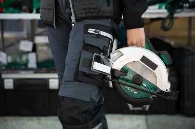 Becerikli bir işçi, inşaat ve işçilikteki hayati rolünü sembolize eden dairesel bir testere tutar.