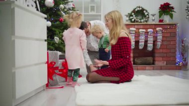 Neşeli bir aile süslenmiş bir Noel ağacının etrafında toplanıyor, sevgi ve kahkahalarla neşeli anılar yaratıyor.