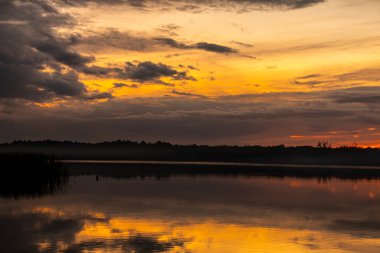 Nefes kesen bir günbatımı dingin ve sakin göl manzarası üzerine canlı ve büyüleyici renkler döküyor.