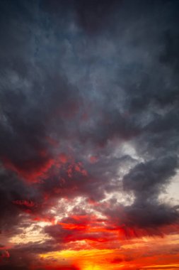 Çarpıcı ve nefes kesici bir gün batımı dramatik bulutların arasında geniş gökyüzünü canlı renklerle resmediyor.