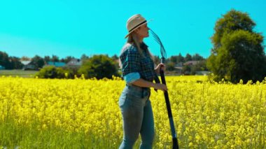 Şık şapkalı bir kadın hayat dolu sarı bir çiçek tarlasına bakar. Doğayı ve huzuru kucaklar.