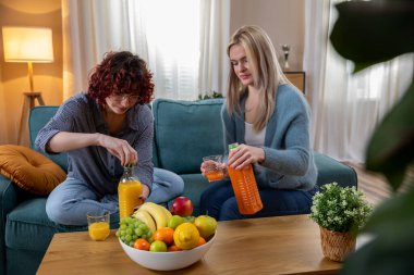 İki yakın arkadaş canlı ve renkli meyveler kullanarak taze ve lezzetli meyve suyu yaparken çok eğleniyorlar.