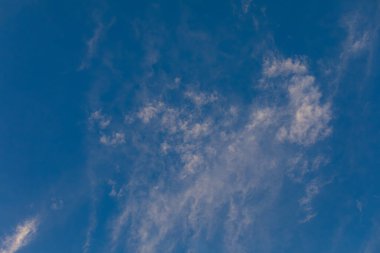Sakin ve huzurlu mavi bir gökyüzü narin, ince bulutlarla bezenmiş, açıklık hissi vermek için mükemmel.