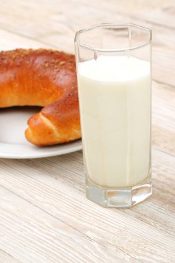 Kırsal bir masada lezzetli ve ağız sulandıran bir hamur işinin yanında servis edilen ferahlatıcı bir bardak soğuk süt.