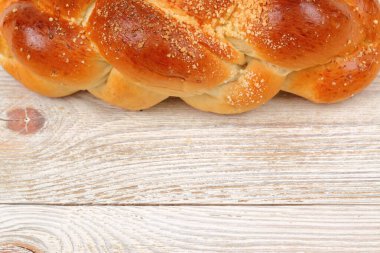 Çok güzel örülmüş bir challah ekmeğinin içinde, ahşap bir arka planda mükemmel altın ve çıtır çıtır bir kabuk.