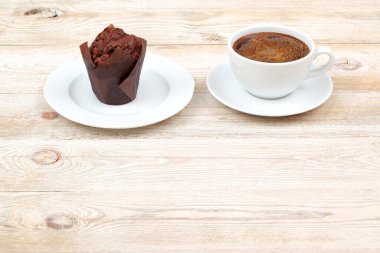 Lezzetli bir çikolatalı kek, kırsal bir ahşap masada, dumanı üstünde bir fincan kahvenin yanında servis edilir.