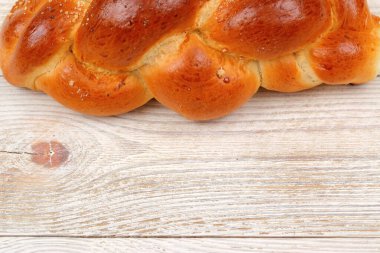 Altın, örülmüş challah ekmeği güzel bir ahşap masada dinleniyor, her kutlama ve yemek için mükemmel.
