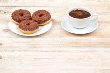 Keyifli ve rahat bir anın tadını çıkarın çikolatalı çöreklerin ve taze kahvenin tadını çıkarın kırsal ahşap bir masada
