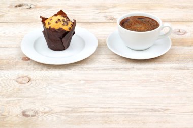 Enfes, taze pişmiş kek, ahşap bir yüzeyde dumanı tüten bir fincan sıcak kahveyle mükemmel bir şekilde eşleştirilir.