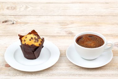 Kırsal bir ahşap masada, sıcak bir öğle tatili için mükemmel bir kahve fincanı ile enfes bir kek.