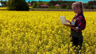 Bir kadın canlı sarı bir çiçek tarlasında dizüstü bilgisayar kullanarak doğa ve teknolojiyi kusursuz bir şekilde harmanlıyor.