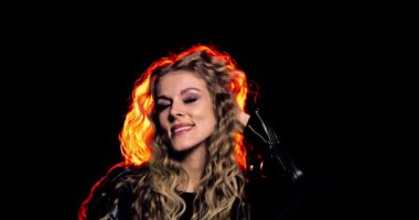 Zarif saçları olan ve arka planda çarpıcı ışık saçan bir kadının büyüleyici bir portresi..