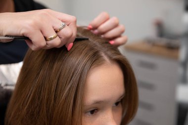 Üst düzey bir kuaförde yetenekli bir stilist şık, modaya uygun bir saç stili çizmek için dikkatli parçalar ve stil yapar.