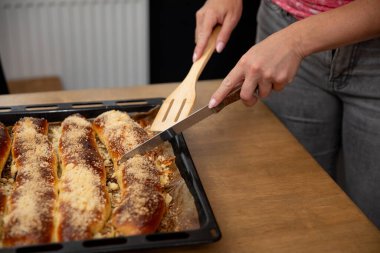 Bir insan peynirli bir yemeği ustalıkla dilimliyor, güzel bir şekilde sergiliyor enfes ev yemekleri yapıyor.