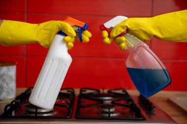 Renkli bir mutfakta, uzayda temizlik ve düzeni sağlamak için iki el enerjik bir şekilde sprey sıkar.