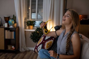 Genç bir kadın, güneş gözlüğü takarak rahat bir anın tadını çıkarıyor. Huzur ve rahatlık hissi yayıyor.